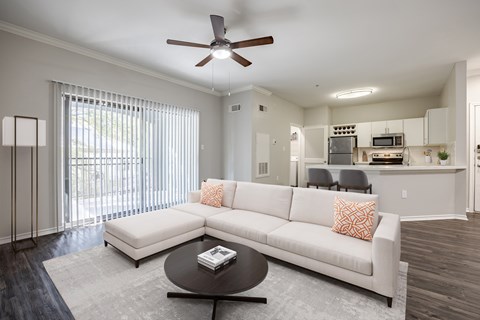 A modern living room with a white couch and a ceiling fan.