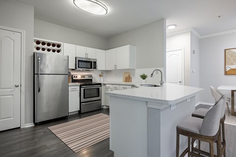A kitchen with a white counter top and a striped rug on the floor.