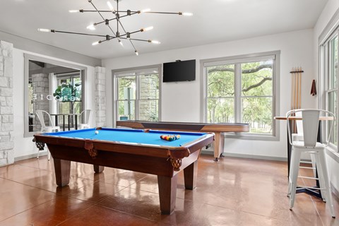 A pool table in a room with a television and a chair.