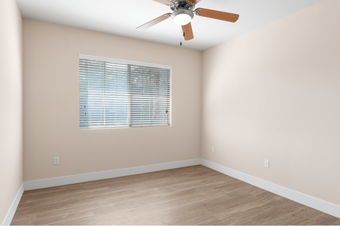 A room with a ceiling fan and a window with blinds.