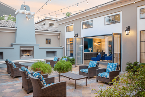 A patio with a fireplace and chairs.