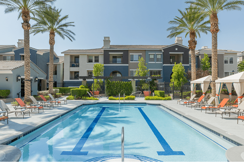 A swimming pool surrounded by palm trees and lounge chairs.