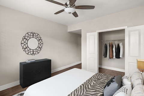 A bedroom with a bed, a ceiling fan, and a wreath on the wall.