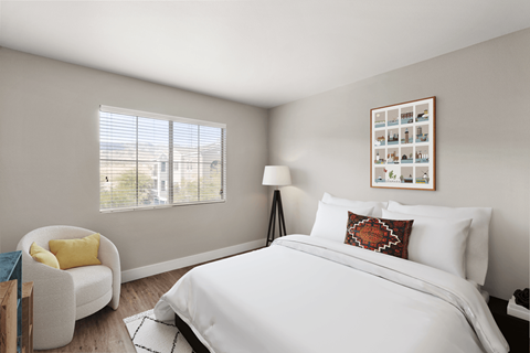 A bedroom with a large bed, a chair, and a window with blinds.