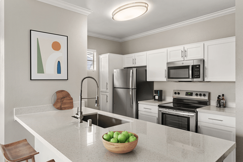 A modern kitchen with a bowl of green apples on the counter.