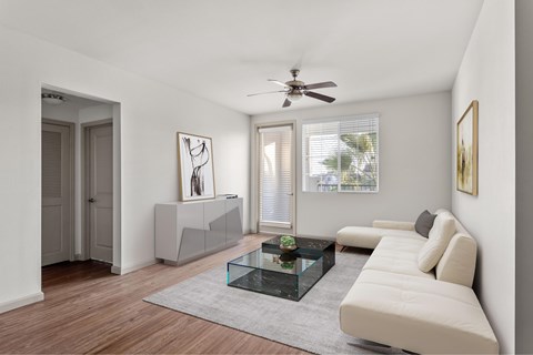 A modern living room with a glass coffee table and a white sofa.