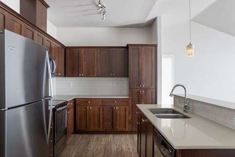 A kitchen with a stainless steel refrigerator and wooden cabinets.