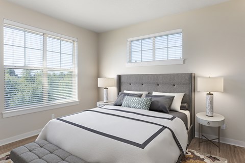 A bedroom with a large bed and a window with blinds.