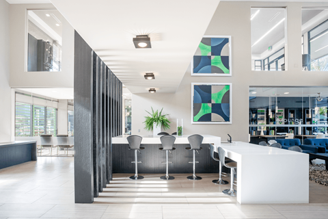 A modern office lobby with a white reception desk and a large abstract painting on the wall.