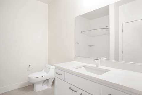A white bathroom with a toilet, sink, and mirror.