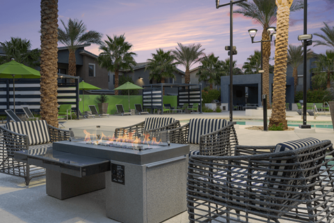 A patio with a fire pit and chairs.