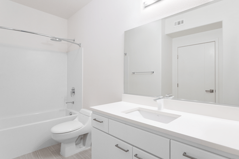 A white bathroom with a toilet, sink, and mirror.