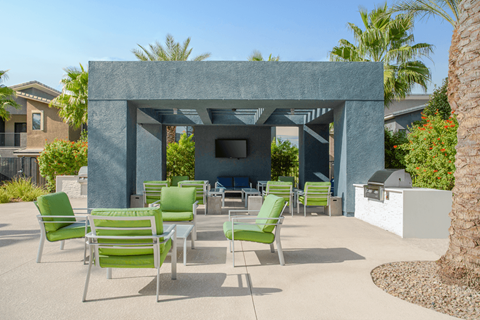 A patio with green chairs and a grey concrete structure.
