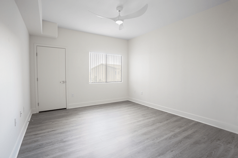 A room with a white door and a window with bars on it.