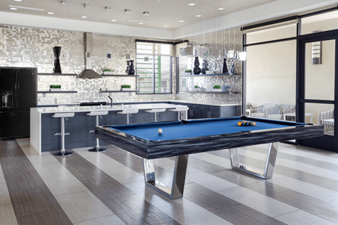 A pool table is in the middle of a kitchen and dining room.
