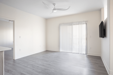 A room with a television and a window with blinds.