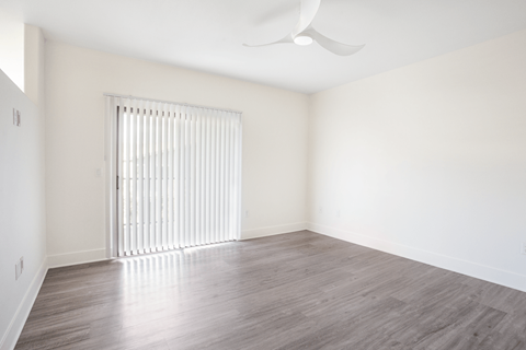 A room with a window covered by white blinds and a ceiling fan.