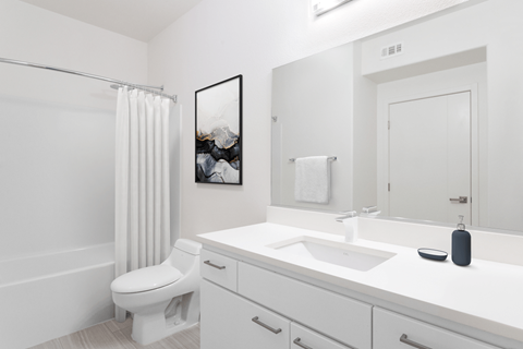 A white bathroom with a toilet, sink, and mirror.