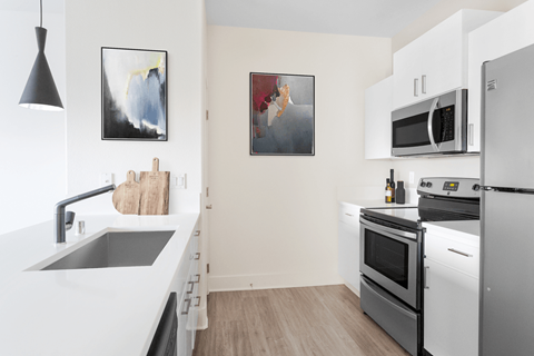 A modern kitchen with white appliances and a wooden floor.