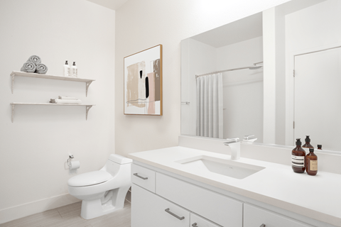 A white bathroom with a toilet, sink, and mirror.