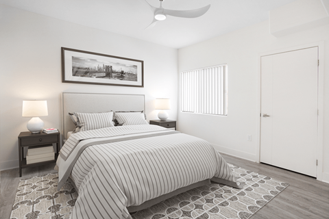 A bedroom with a bed, two lamps, and a picture on the wall.