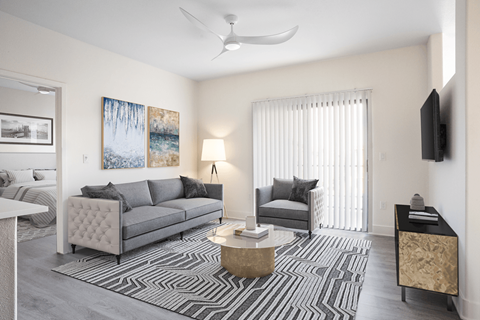 A living room with a grey couch, a black and white striped rug, and a painting on the wall.