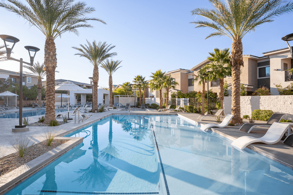 A swimming pool surrounded by palm trees and lounge chairs.