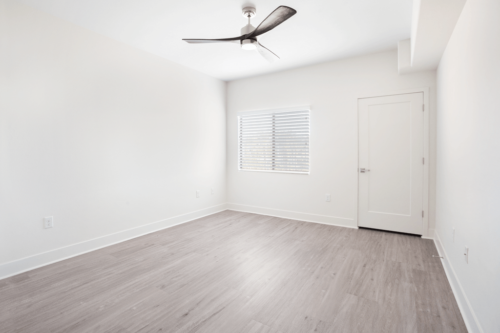 A room with a ceiling fan and a door.