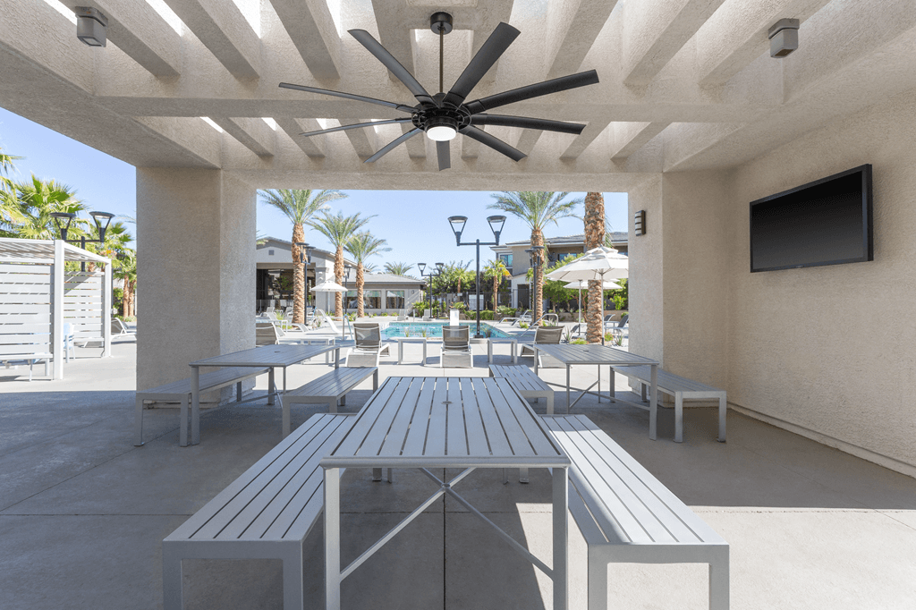 A patio with a table and chairs and a ceiling fan.