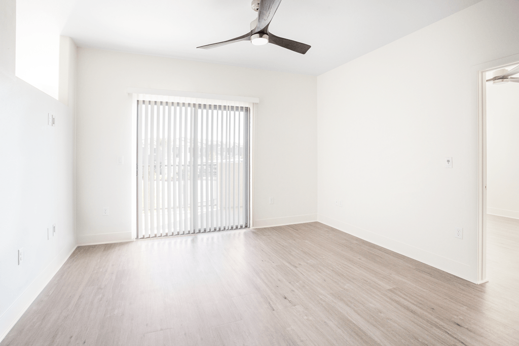 A room with a ceiling fan and a window with blinds.