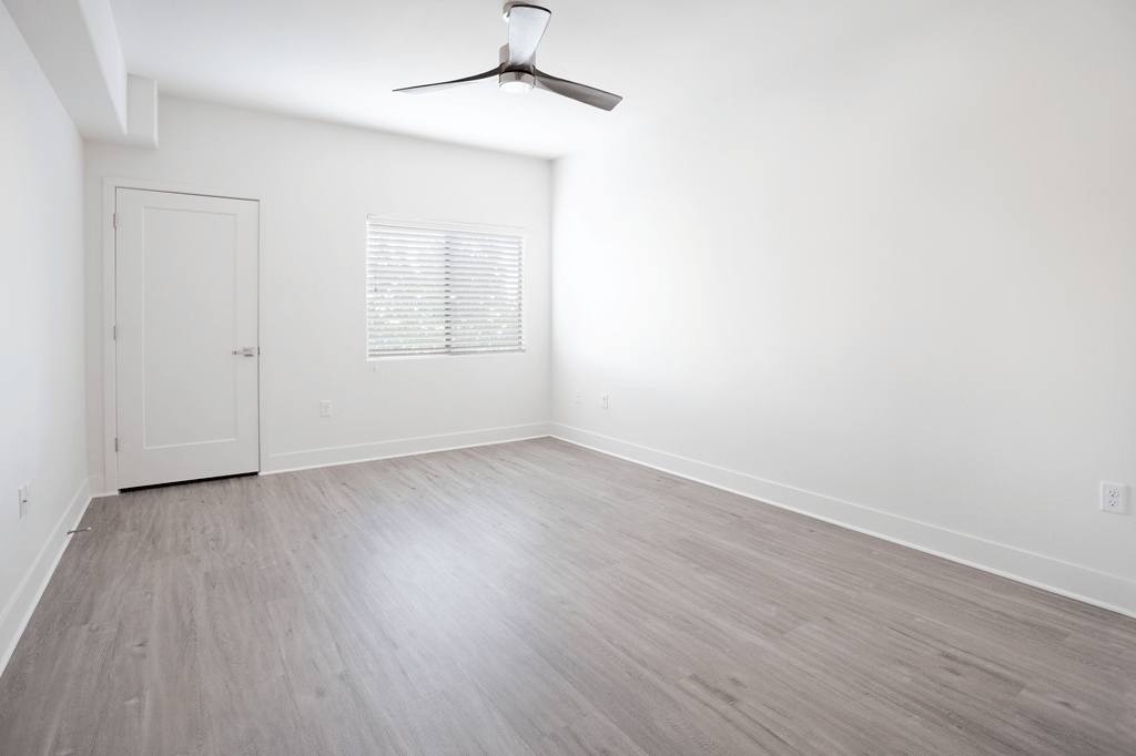 A room with a ceiling fan and a door.