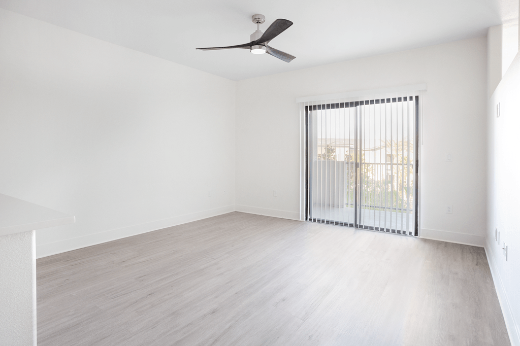 A room with a ceiling fan and sliding glass doors.
