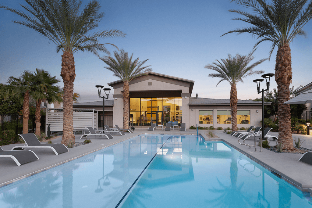 A swimming pool surrounded by palm trees and lounge chairs.