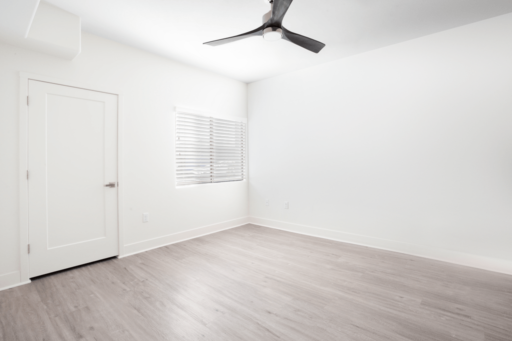 A room with a ceiling fan and a door.