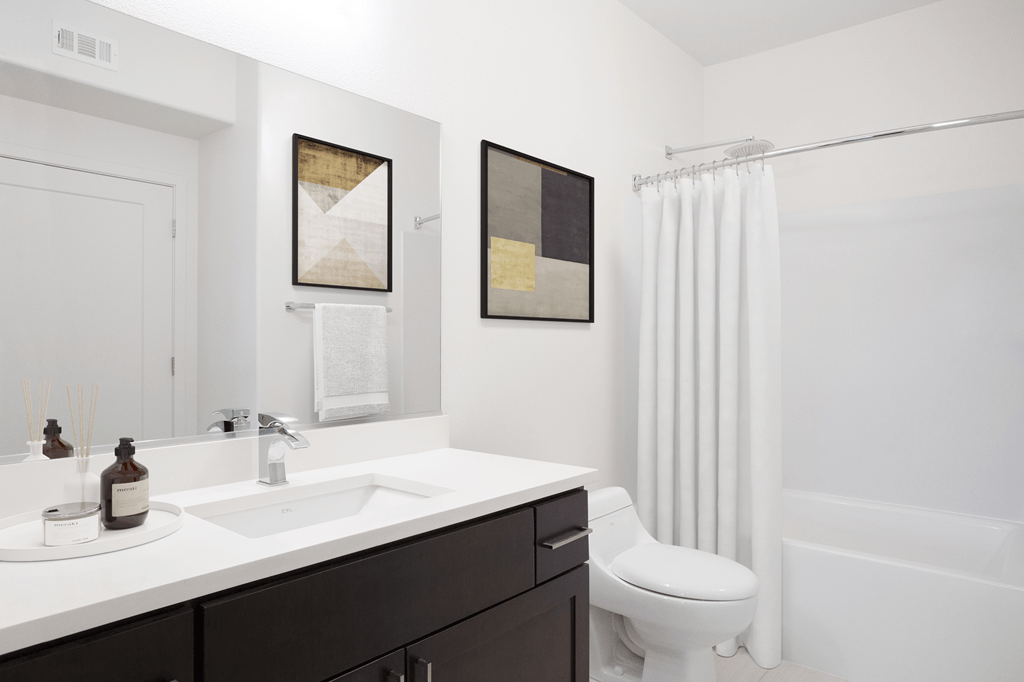A white bathroom with a toilet, sink, and two pictures on the wall.