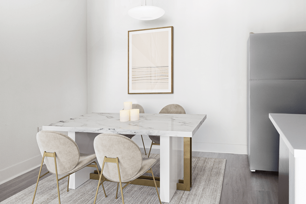 A white marble dining table with four chairs and a framed piece of artwork on the wall.