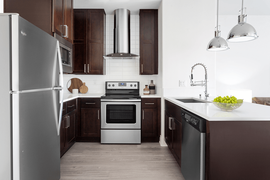 A modern kitchen with dark wood cabinets and stainless steel appliances.