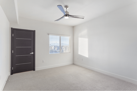 A room with a ceiling fan and a door.