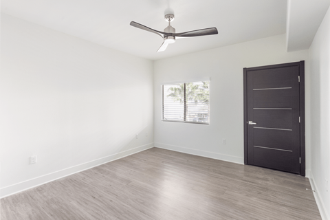 A room with a ceiling fan and a door.