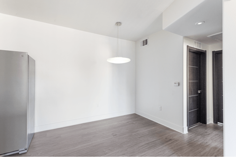 A room with a refrigerator and a light hanging from the ceiling.