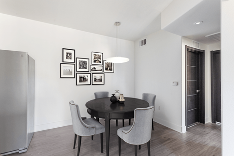 A modern dining room with a round table and grey chairs.