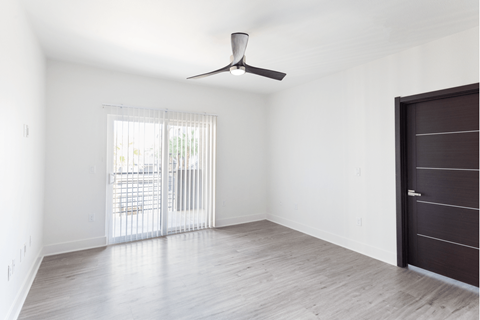 A room with a ceiling fan and a sliding glass door leading to a balcony.