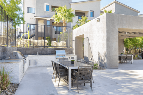 A patio with a table and chairs is in front of a house.