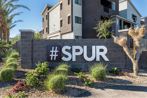 A wall with the hashtag #SPUR is in front of a building.