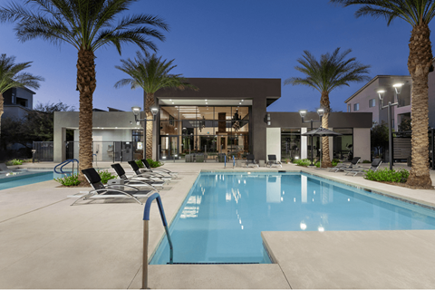 A swimming pool surrounded by palm trees and lounge chairs.