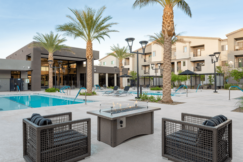 A poolside area with a table, chairs, and palm trees.