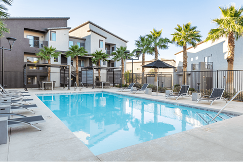 A swimming pool surrounded by lounge chairs and palm trees.