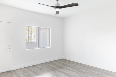 A room with a ceiling fan and a window with blinds.