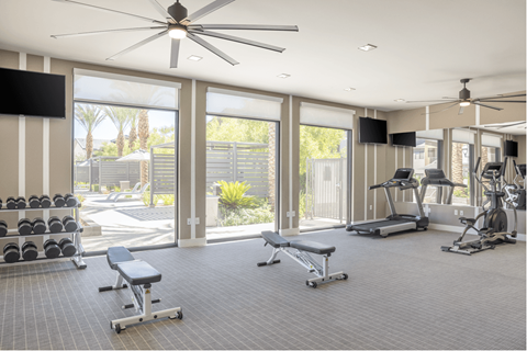 A spacious gym with a variety of equipment and a ceiling fan.