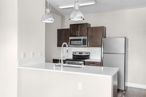 A modern kitchen with a white countertop and stainless steel appliances.